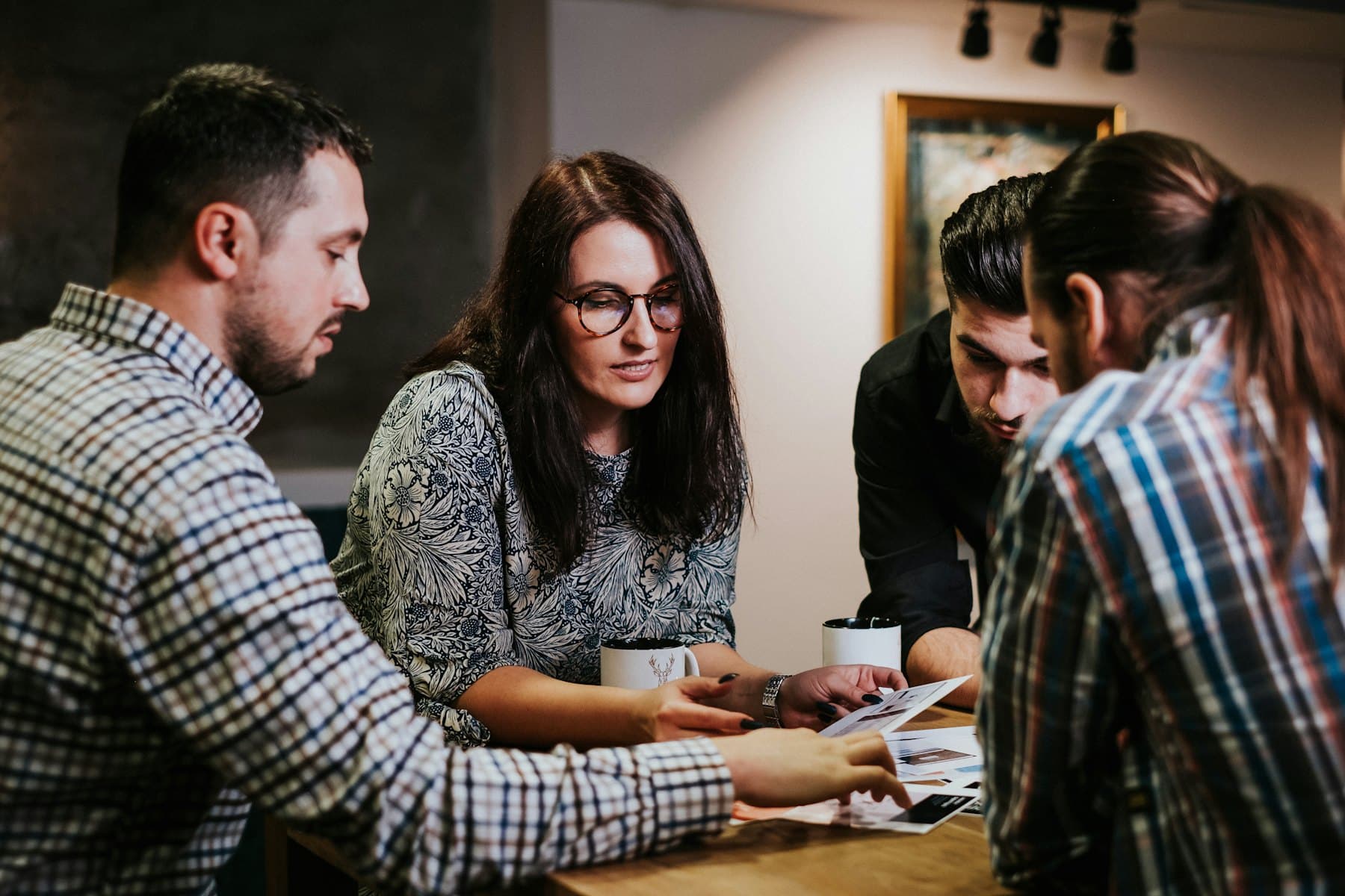 Four colleagues gathered around a table, reviewing printed documents together